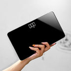 Digital bathroom scale held by a hand with a light gray background